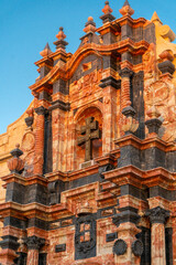 pink and black marble facade of the church of caravaca de la cruz, with the golden light of sunset and a blue cloudless sky