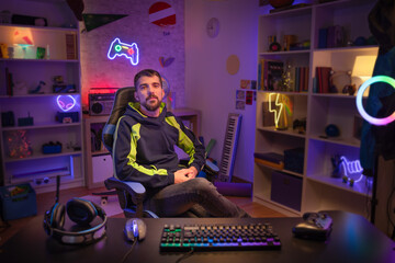 Gamer at his room portrait looking to the camera with Colorful Neon Led Lights.