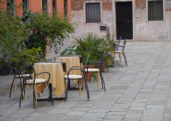 Outdoor sitting area with table, chairs, plants and no people.  Empty closed restaurant exterior, Mediterranean style furniture and dining out concept