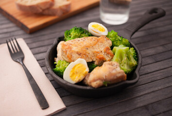 chicken breast with broccoli and quail eggs in small cast iron skillet