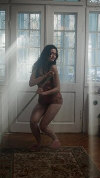 A girl holding a brush and dancing in the corridor, being playful 