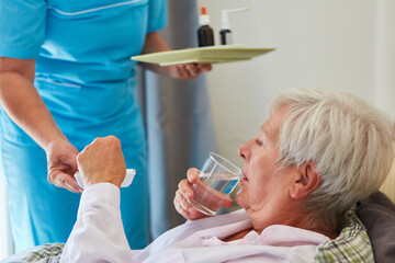 Elderly woman takes a tablet with a sip of water