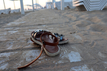 Sandals on a white wooden track covered with sand. Beach