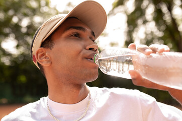 Young man in sun visor with a bottle of water in hands - obrazy, fototapety, plakaty