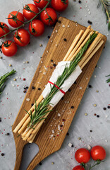 Italian grissini on a cutting board with vegetables
