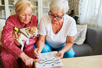 Elderly caregiver and senior citizen solving the crossword puzzle
