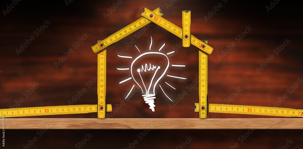 Poster folding ruler in the shape of a house and a design of a light bulb, above a wooden workbench with co