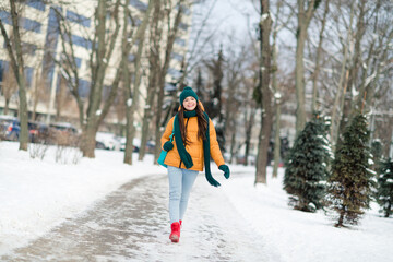 Full length body size view of attractive cheerful preteen girl wearing warm outfit going to school december snowy day outdoors