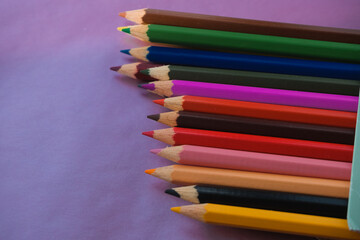 multicolored pencils on purple background, school, drawing hobby and bright life colors concept