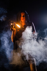 Obraz premium Young girl in a long black coat fire night.