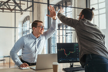 co-worker traders giving high five to each other celebrating successful deal at stock exchange...