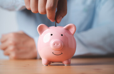 Businessman putting coin to pink piggy bank for money saving and deposit to investment and profit of retirement concept.