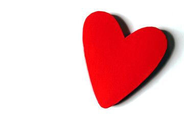Red lacquered heart shaped box on the right of a white surface with copy space on the left....