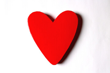 Red lacquered heart shaped box, centred on a white surface with copy space on both sides. Horizontal.