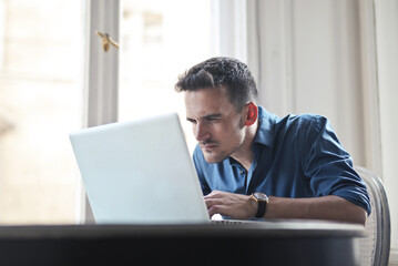 young man looks carefully at his computer screen