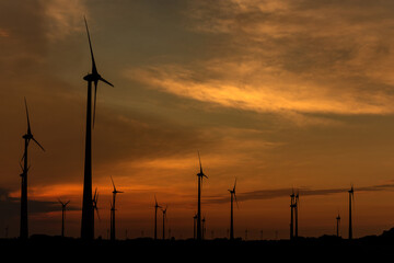 Silhouettes of wind turbines producing renewable energy at sunset