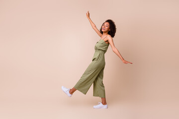 Full size photo of lovely young girl wavy hair dancing celebrate weekend dressed stylish khaki clothes isolated on beige color background