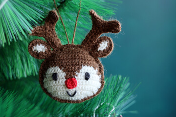 Obraz premium Cute hand made Christmas ornament. Crochet Reindeer close up photo. Cozy winter present ideas. 