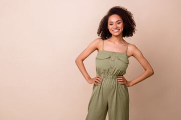 Fototapeta premium Photo of gorgeous cute nice satisfied woman with wavy hairstyle dressed khaki overall arms on waist isolated on beige color background