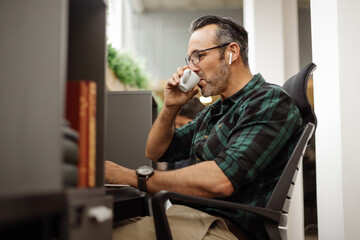 Business man at hot desk in co working office space, drinking coffee