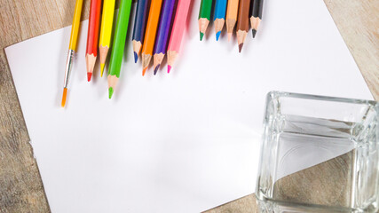 Colorful watercolor pencils and brushes on a white background. View from above.