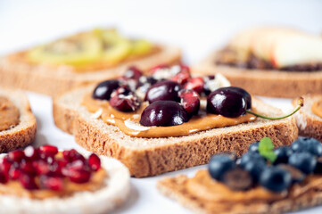 Various kind of open sandwiches with berries and fruits. Made from bread, such as wholegrain, rice crakers, crispbreads and different nut butter, such as peanut, crunchy cashew and almond butter