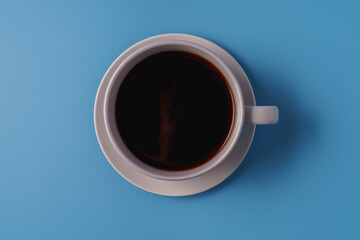 A cup of black coffee on blue background, top view.