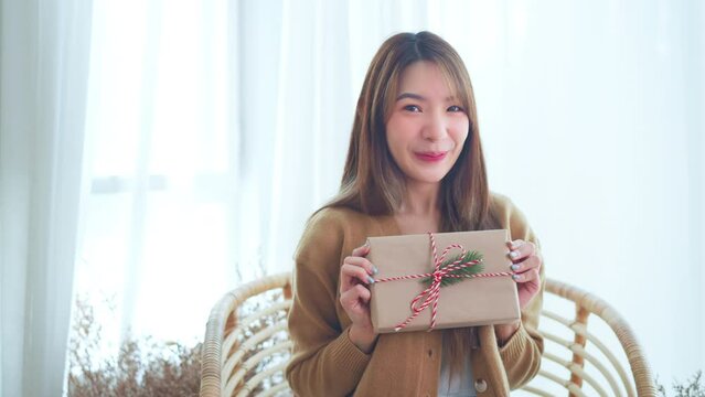Giving a gift, Happy young asian woman giving handmade present wrapped paper. Christmas time. New Year's Eve and gift giving