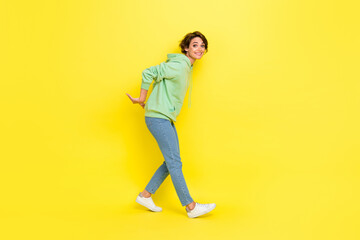 Fototapeta na wymiar Full length photo of funny pretty girl dressed green sweatshirt stealing arms empty space isolated yellow color background
