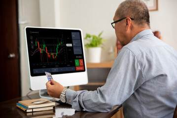 Senior asian man using computer trading stock market exchange online at home.