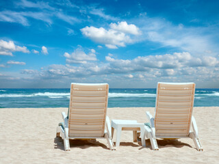 Two sun beach chairs on shore near ocean