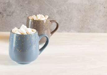 Two cups of cocoa with marshmallows on a light background with a copy space