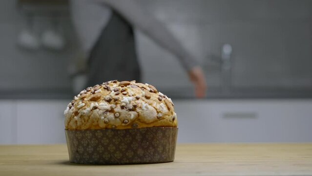 Traditional Italian homemade Christmas panettone typical Milanese with almonds, chocolate chips and sugar, with a woman moving in the background