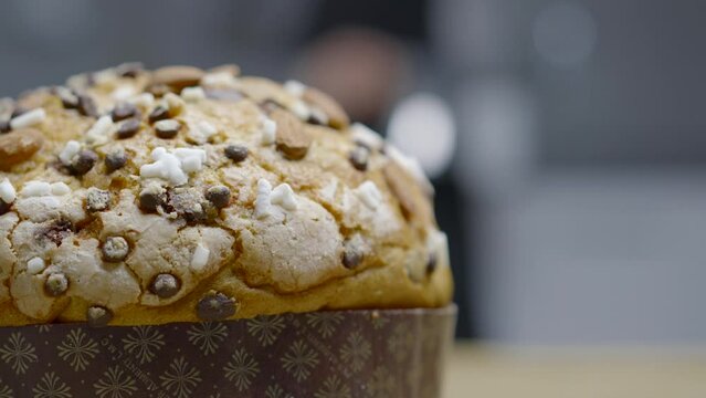 Traditional Italian homemade Christmas panettone typical Milanese with almonds, chocolate chips and sugar, with a woman moving in the background