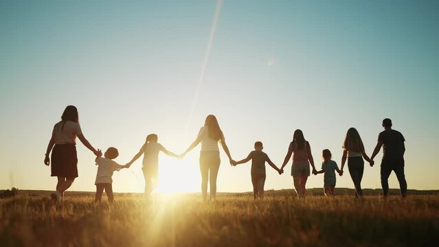 community large family in the park. a large group of people holding hands walking silhouette on nature sunset in the park. big family kid dream lifestyle concept. people in the park. large family