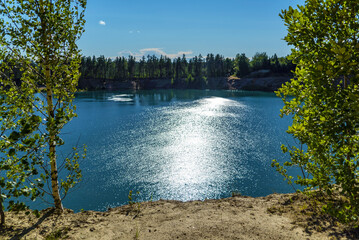 Sun glare on the water . The steep shore of the reservoir.