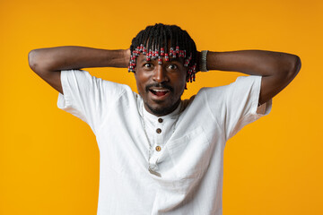 Shocked african man opening mouth widely on yellow studio background