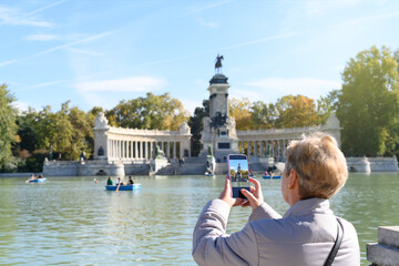 Retiro Park photographed by a unrecognizable woman with her cell phone. Concept of senior tourism...