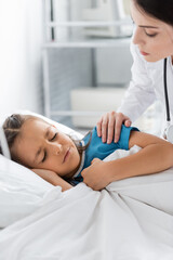 Doctor calming disappointed girl lying on bed in clinic.