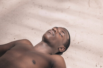 Black man lying on sand