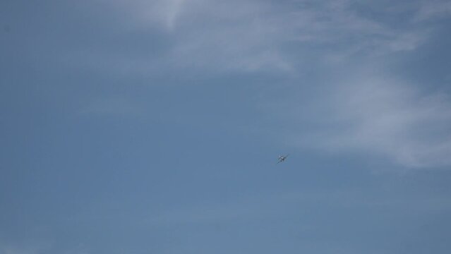 Long shot of flying away small-seat plane in patrially cloudy sky when sunny summer. Plane owned to aircraft school