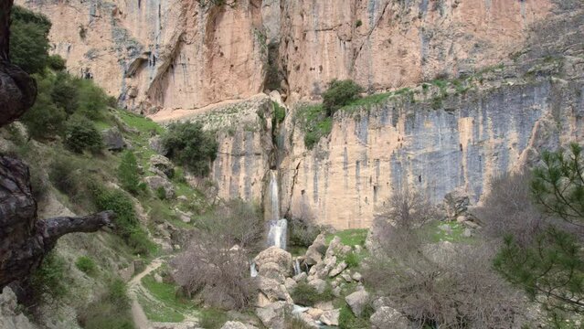 Panoramic view of waterfall and Mediterranean forest. Aerial travelling out.