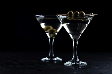 A martini in a triangular glass with olives is on the table