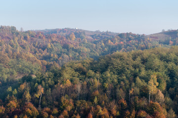 Obraz premium Hills covered with colorful forest in autumn and village houses on top of hills, rural landscape