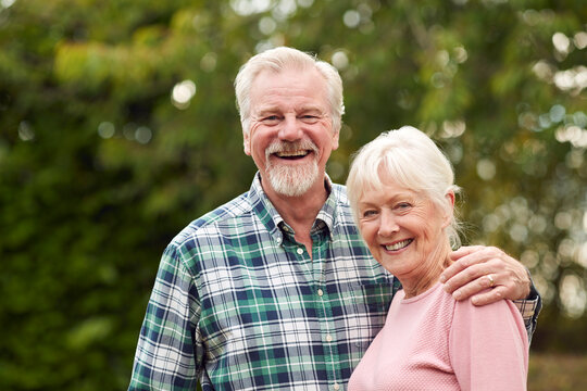 Portrait Of Loving Retired Senior Couple Hugging Outdoors In Countryside Or Garden Together