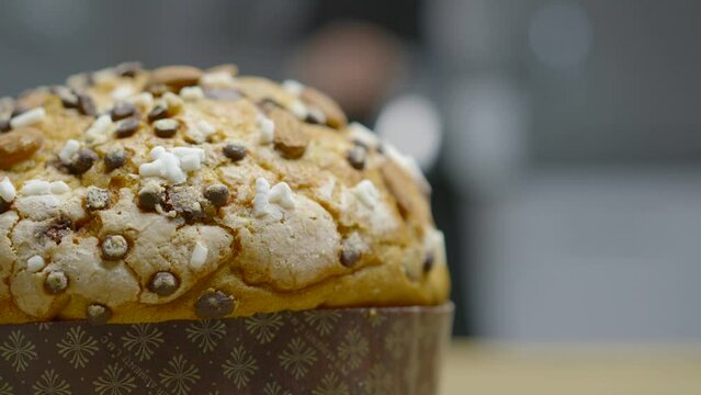 Traditional Italian homemade Christmas panettone typical Milanese with almonds, chocolate chips and sugar, with a woman moving in the background