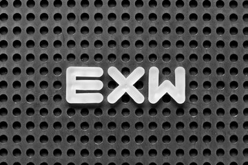 White alphabet letter in word EXW (abbreviation of Ex works)  on black pegboard background