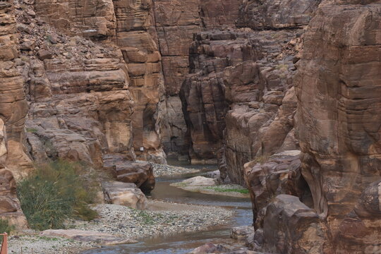 Entrance to the Wadi Mujib canyon in Jordan. Steep rocks and a rapid flowing river carved. Difficult crossing and attraction for tourists on the water route.