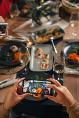 close up of man photographing food with mobile phone at dinner party