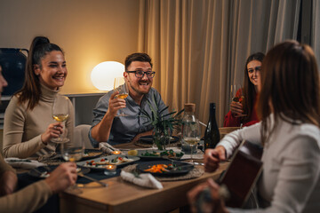 friends celebrating singing and playing guitar at home dinner party